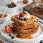 Stack of high-protein French toast with syrup and butter on a white plate